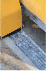 Close-up of a yellow curb or barrier on a concrete surface with visible wheel marks and textured pavement.